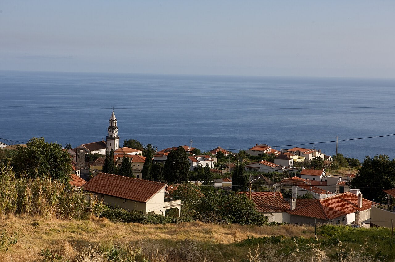 The church and hillside houses of Arco da Calheta above the sea, a view along the village walk.